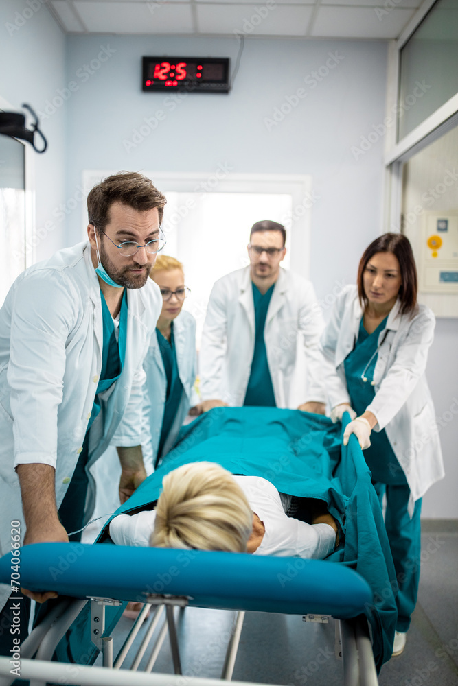 Fototapeta premium Nurses and doctors in a hurry taking patient to operation theatre. Patient on hospital bed pushed from surgeons to emergency theatre. Team of doctors and surgeon rushing patient.