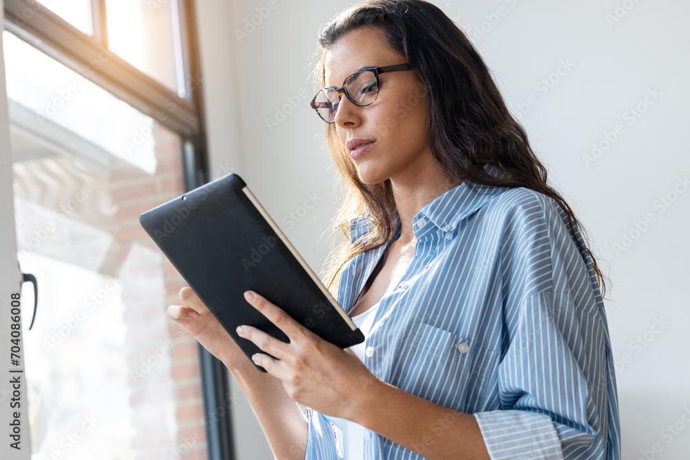 Fototapeta premium Beauty business woman using her digital tablet while sitting on a desk in a modern startup office