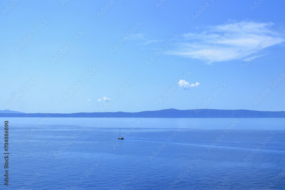 Blue Sea waves and mountains. Blue ocean background. Beautiful crystal clear sea water in Croatia. Beautiful landscape with turquoise water. Vacation and summer concept. Boat at sea