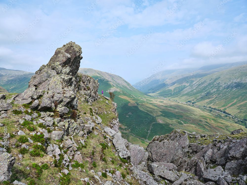 Summit of Helm Crag with hiker looking down to Dunmail Raise, Lake District, UK Summit of Helm Crag with hiker looking down to Dunmail Raise, Lake District, UK