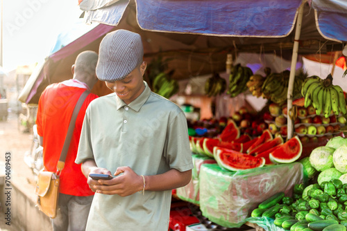 young african vegetables trader using cellphone in marketplace