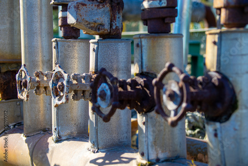 three old and rusty industrial liquid control faucets. One in each tube aligned parallel with differentiated focus