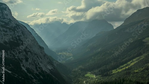 Timelapse of moving clouds and sunbeams over valley in Karwendel mountains during sunny blue sky day in summer from above, sunbeams breaking through white clouds in the sky, Tyrol Austria. photo