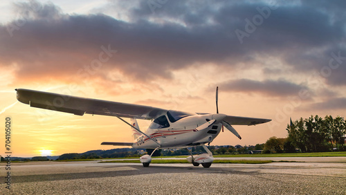 Kleinflugzeug auf der Rollbahn eines Landeplatzes mit untergehender Sonne im Hintergrund photo