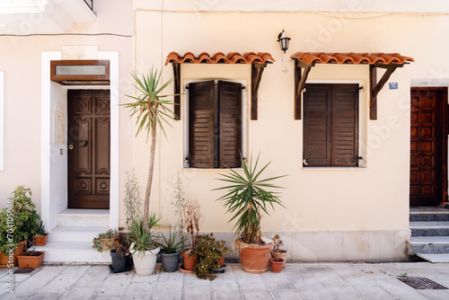 Traditional Mediterranean home exterior with wooden shutters and an array of potted plants enhancing the quaint, welcoming vibe © arthurhidden