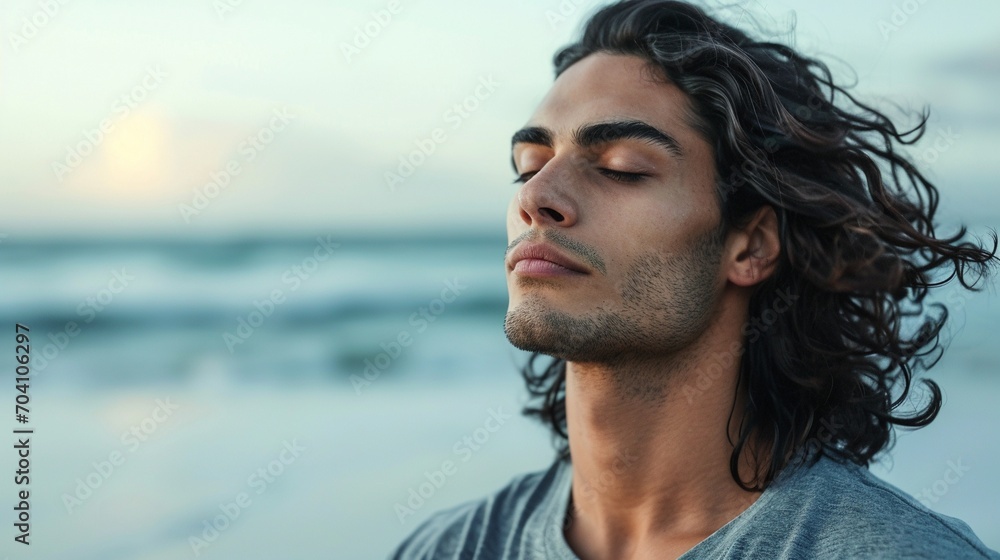 Close up of handsome medium-aged meditating man with gray hair and beard on the ocean shore, with closed eyes - obrazy, fototapety, plakaty 