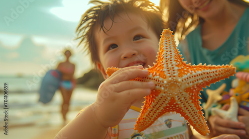 Enfant heureux à la plage avec sa mère montre une étoile de mer à la caméra photo
