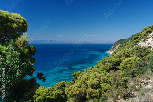 Breathtaking view of the deep blue sea from high above, with lush greenery adorning the rugged cliffs of a pristine coastline © arthurhidden
