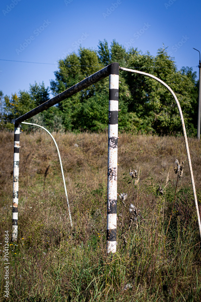 Football goal on the field among the grass against the background of deciduous trees Football goal on the field among the grass against the background of deciduous trees