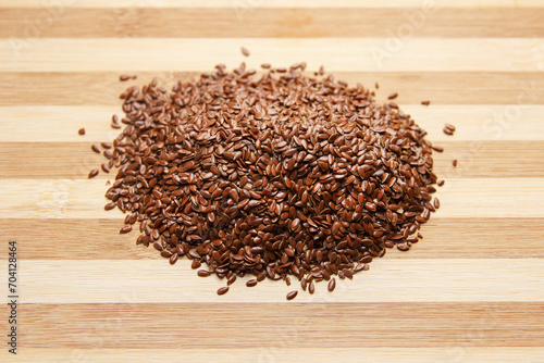 Many linen raw seeds lie on a wooden surface in the kitchen. Top view.