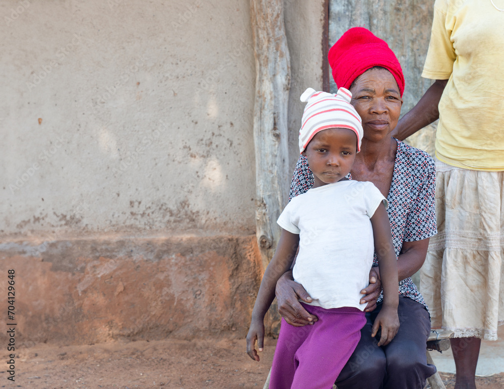 village african family mother and child , standing in the yard daytime, in front of the shack village african family mother and child , standing in the yard daytime, in front of the shack