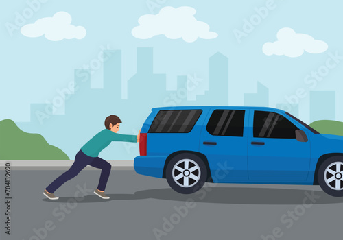 Young man pushing a broken car on the road
