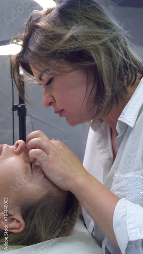 Eyelash extensions. Eyelash extension procedure in beauty salon by professional stylist. Close-up. Lengthening of eyelashes. Master and client in beauty salon. Beauty and fashion. 4k footage.