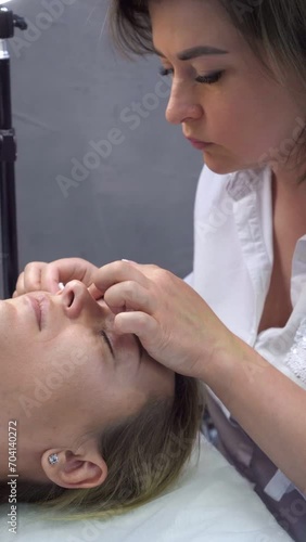 Professional stylist pretty woman gently cleanses skin of eyelids and under eyes of client with cotton pads in beauty salon. Eyelash extension. Master and client. Beauty . 4k footage.