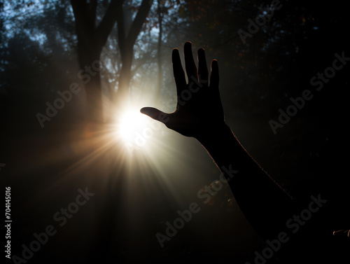 Silhouette of a hand reaching upwards seeking help from a light source