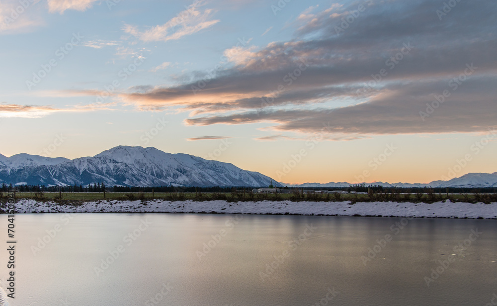 Mount Hutt and Canterbury Plains at sunset with frozen dam in foreground