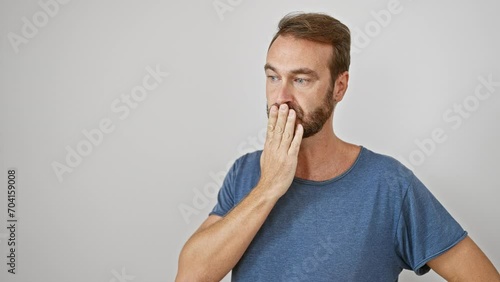 Shocked middle-aged hispanic man standing in silence, hand covering mouth in surprise - isolated white background portrays the emotion of fear from a secret mistake. photo
