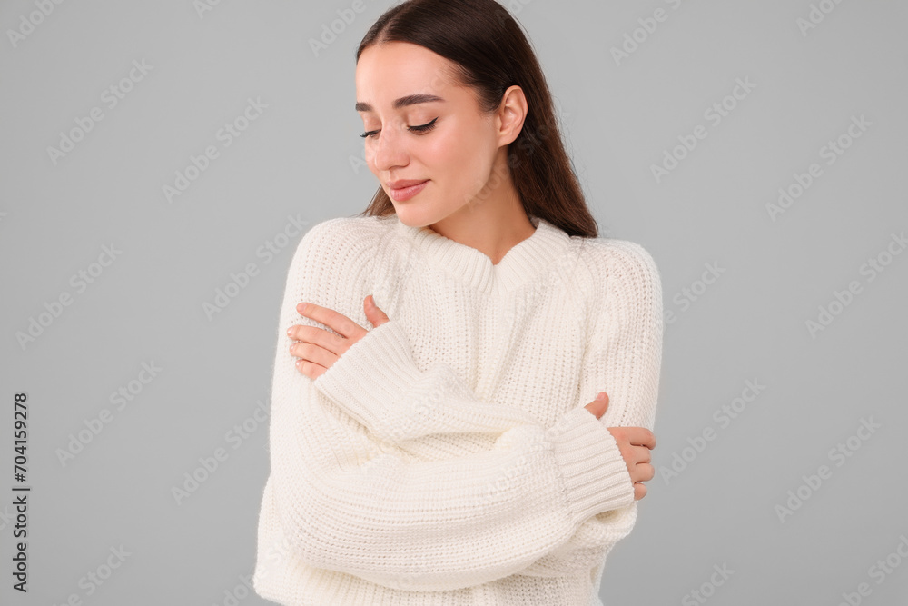 Beautiful young woman in stylish warm sweater on grey background Beautiful young woman in stylish warm sweater on grey background