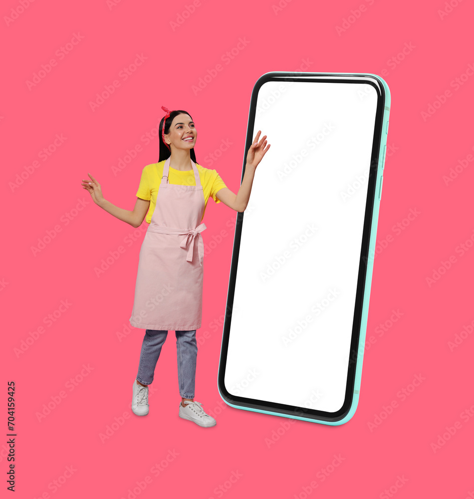 Housewife using big smartphone on pink background Housewife using big smartphone on pink background