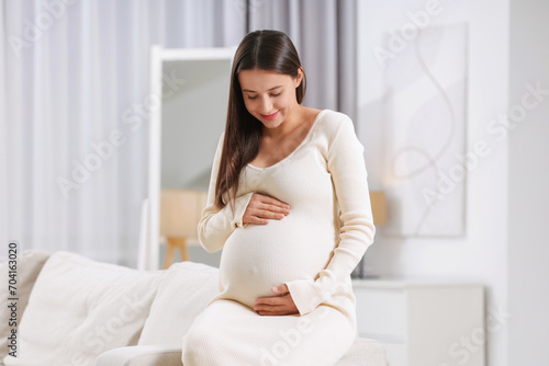 Free Download Beautiful pregnant woman sitting on sofa at home - GFXLoad