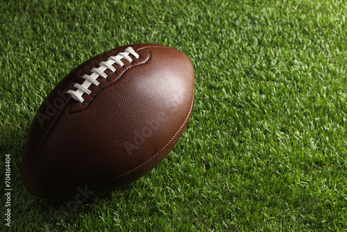 Leather American football ball on green grass. Space for text photo