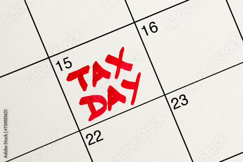 April 15th highlighted in red as Tax Day on a white calendar for income tax filing reminder, flat lay, top-down view, handwriting with red marker