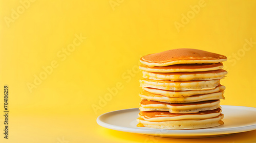 Stack of tasty pancakes with honey on pastel yellow background. Copy space for text