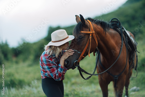Happy blonde with horse in forest. Woman and a horse walking through the field during the day. Dressed in a plaid shirt and black leggings. © svetograph