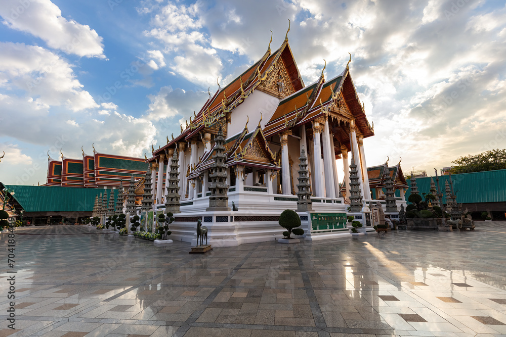 Fototapeta premium Wat Suthat in Bangkok, Thailand. Royal Temple constructed in 1807. Polished Marble floor in foreground; blue sky, sunlit clouds overhead.