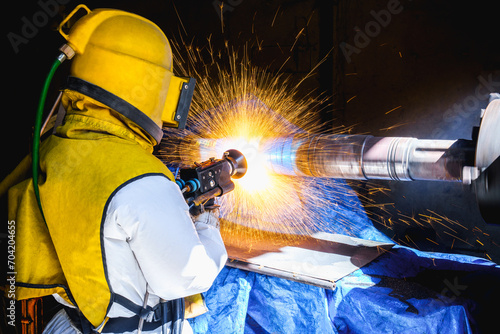 Technician operator repair outside diameter shaft gear by wire arc spraying fusion stainless steel coating process in factory workshop.
