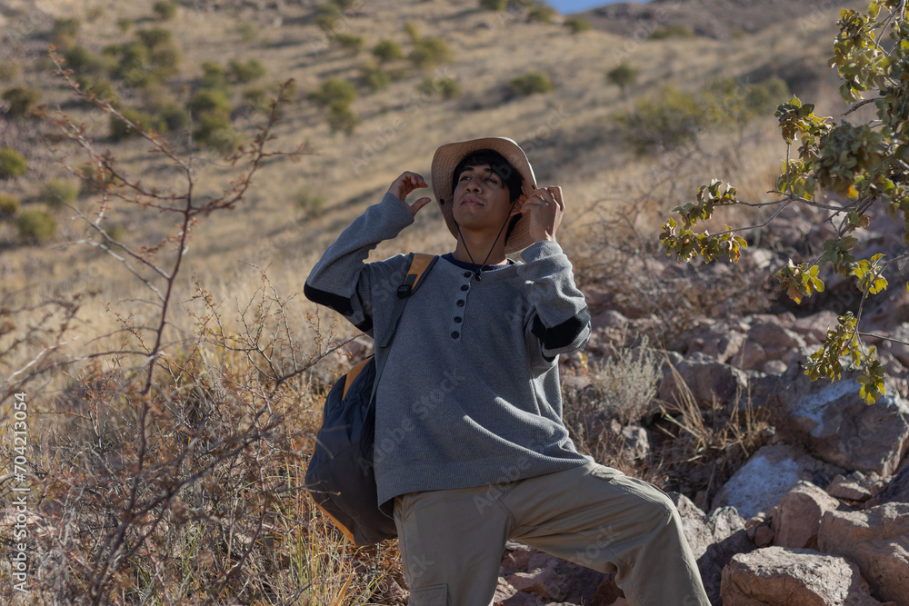 Naklejka premium Young man with backpack wears hat on his vacation to protect himself from the sun for hiking in a mountain in Mexico