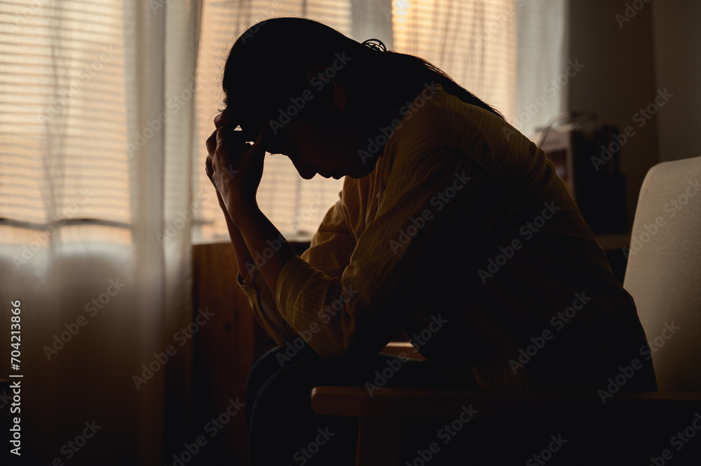 Silhouette photo of young Asian woman feeling upset, sad, unhappy or disappoint crying lonely in her room. Young people mental health care problem lifestyle concept. Silhouette photo of young Asian woman feeling upset, sad, unhappy or disappoint crying lonely in her room. Young people mental health care problem lifestyle concept.
