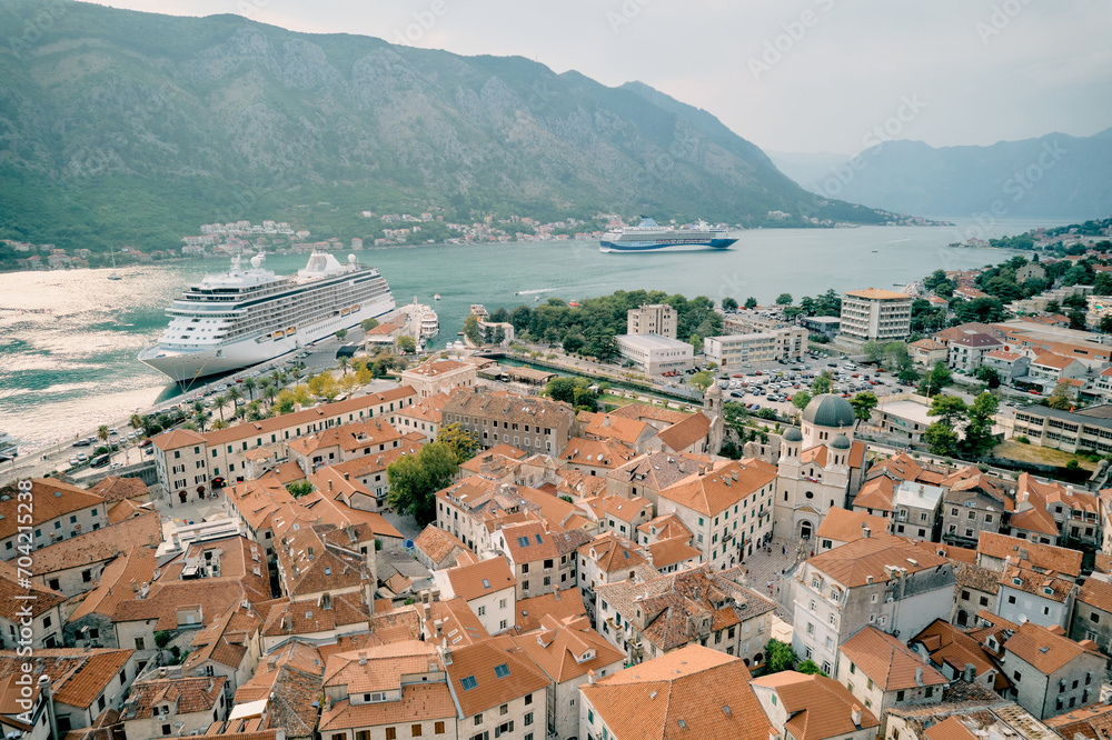 View over the red roofs of old houses to a large liner moored off the coast. Kotor, Montenegro. Drone