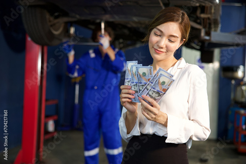 businesswoman or customer holding and counting cashes pay for technician in automobile repair shop
