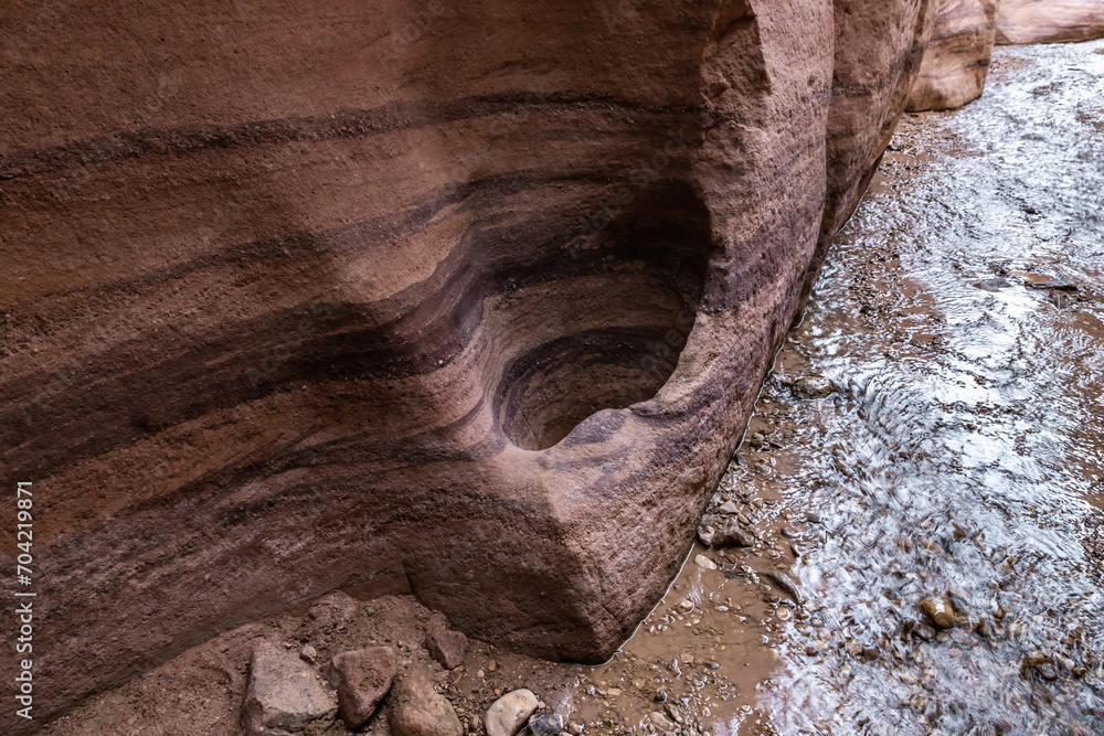 Obraz premium A small niche in rock wall on the bank of a shallow stream on the Wadi Numeira hiking trail in Jordan