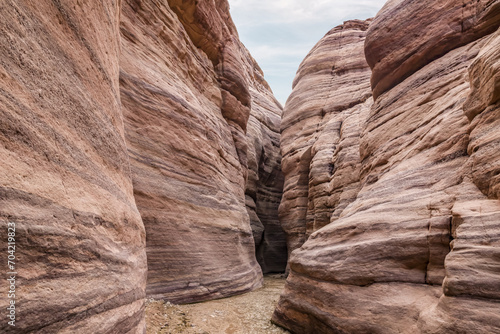 A small  shallow stream flows between high rocks with beautiful amazing patterns on their walls at end of walking trail in the Wadi Numeira gorge in Jordan photo