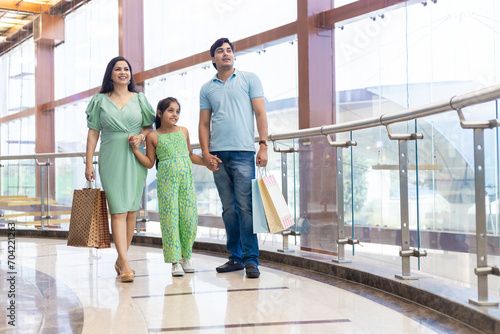 Happy indian family of three enjoying in shopping mall with paper bags, shopping bags in hands. Shopping concept photo