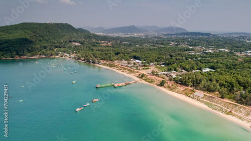 Aerial view of a tranquil tropical coastline with boats, clear turquoise water, and lush greenery, depicting a serene beach destination