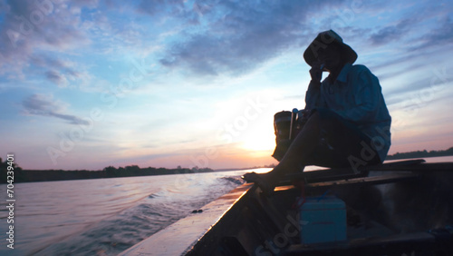Silhouette of a fishermen on boat with outboard motor boat ready to fishing during beautiful sunrise.