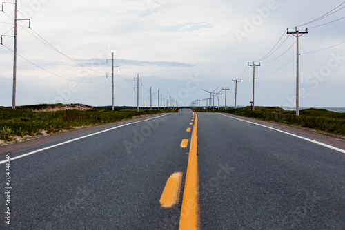 vue sur une route en asphalte grise avec deux lignes jaunes lors d'une journée d'été ennuagée photo