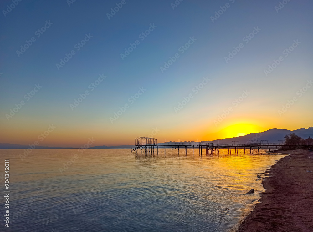 Colorful sunset on the sea. Mountain lake in the rays of the orange sun. Kyrgyzstan, Lake Issyk-Kul. natural background