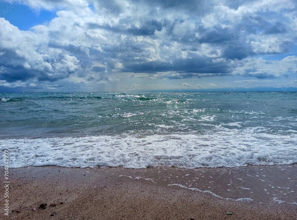 Cumulus clouds over the sea. Dramatic seascape. Waves on the shore. Kyrgyzstan, Lake Issyk-Kul Cumulus clouds over the sea. Dramatic seascape. Waves on the shore. Kyrgyzstan, Lake Issyk-Kul