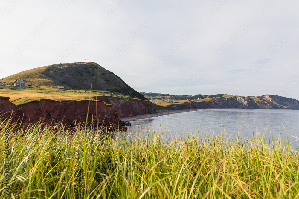 vue sur la côte avec une falaise de roche rouge en bord de mer et du gazon vert sur le dessus en été lors d'une journée ensoleillée