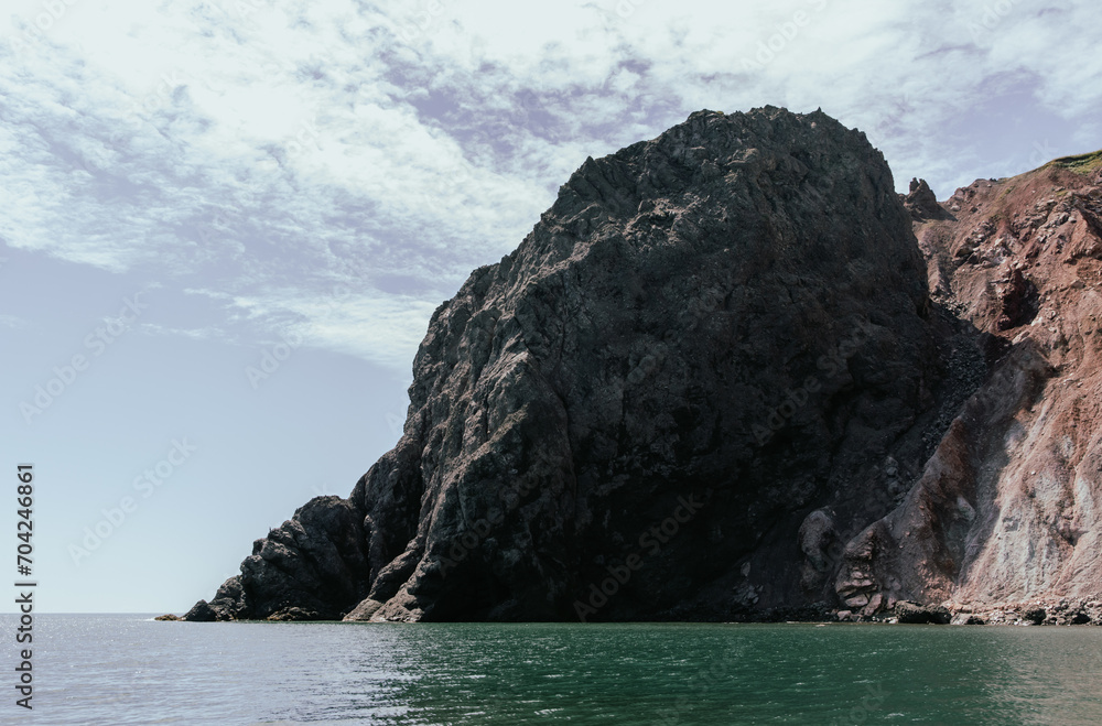 vue sur un gros rocher avec des roches grises pointues dans l'ombre en été au bord de l'eau