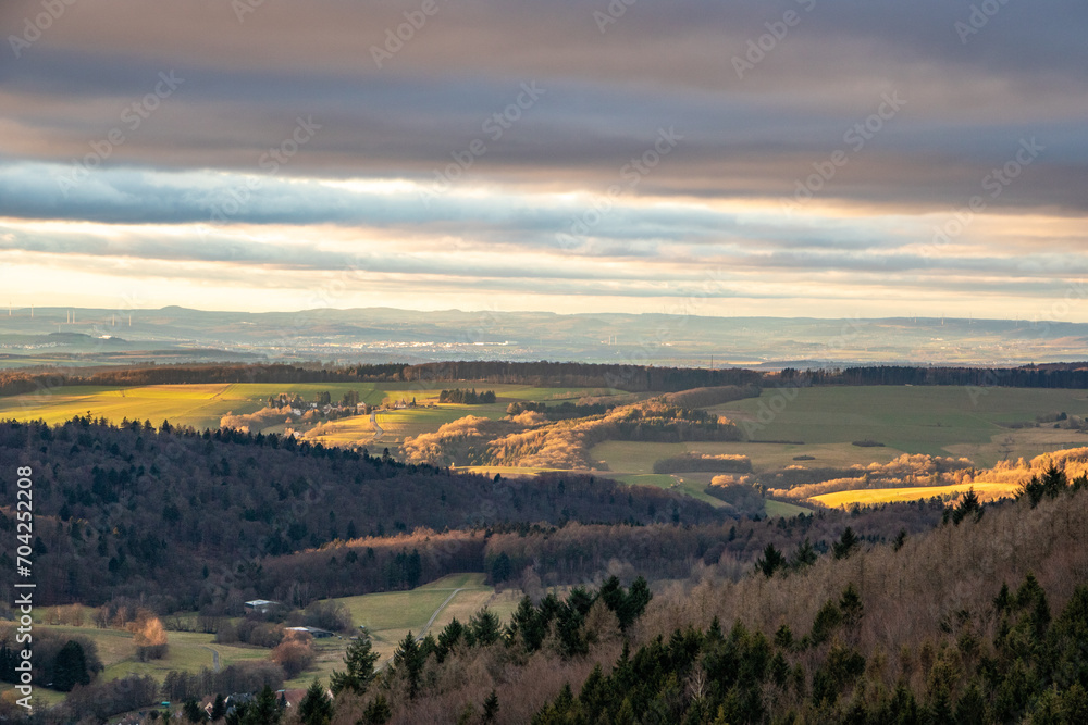 Landscape at the Großer Zacken, Taunus volcanic region. A cloudy, sunny autumn day, meadows, hills, fields and forests with a view of the sunset. Hesse, Germany