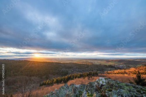 Landscape at the Großer Zacken, Taunus volcanic region. A cloudy, sunny autumn day, meadows, hills, fields and forests with a view of the sunset. Hesse, Germany