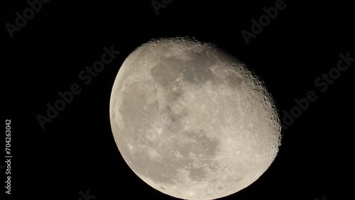 Closeup footage of the waning gibbous moon moving slowly in its orbit in the black night sky photo