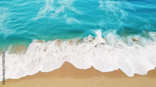  an aerial view of a beach with a wave coming in to the shore and a blue ocean in the background.