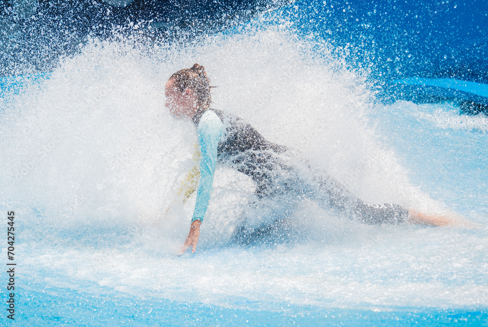 Beautiful young woman surfing on a wave simulator at a water amusement park