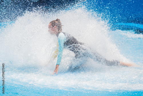 Canvas Print Beautiful young woman surfing on a wave simulator at a water amusement park